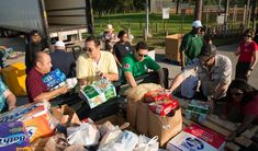 people are standing around boxes and bags of food