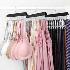 an assortment of bras hanging on a rack in front of white walls and clothes