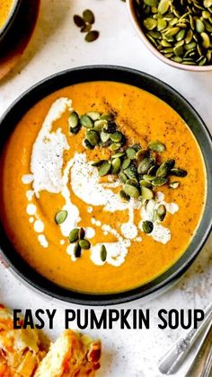 pumpkin soup in a black bowl topped with cream and pistachio seeds next to other dishes