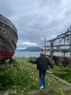 a woman walking towards two boats on land