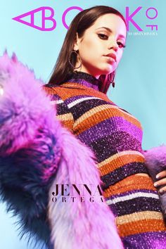 a woman in a purple and black striped dress with fur on her arm, standing next to a blue background