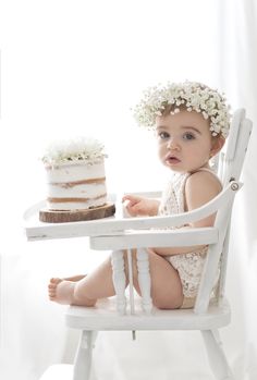 a baby sitting in a chair with a cake