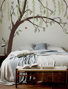 a bedroom with a tree painted on the wall and a bed in front of it