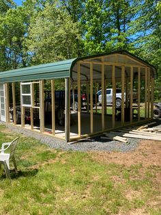 a green metal carport sitting on top of a grass covered field next to a white bench