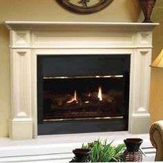 a living room with a fire place in the center and two vases on the table