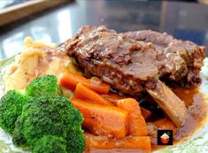 a plate topped with meat, vegetables and gravy on top of a table