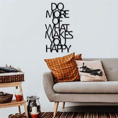 a living room with a couch, table and wall decal that says do more what makes you happy