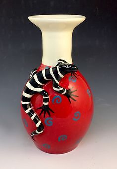 a red vase with a black and white striped gecko on it