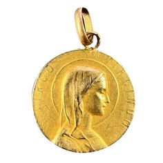 A French 18 karat (18K) yellow gold charm pendant designed as a round medal with a relief of the Virgin Mary in profile with a halo, with the Latin motto 'VIRGO VIRGINUM' (Virgin of Virgins) surrounding. The reverse depicts a book or bible with a sheaf of lilies and the engraved monogram MG/GM. Stamped with the eagle's head for minimum 18 karat gold and French manufacture, along with an incomplete maker's mark.  Dimensions: 1.8 x 1.6 x 0.08 cm (not including jump ring) Weight: 0.92 grams (Chain not included) Gold Heart Locket, Lucky Horseshoe, The Virgin Mary, Locket Charms, Maker's Mark, Vintage Jewels, Heart Locket, Pendant Design, Gold Charm