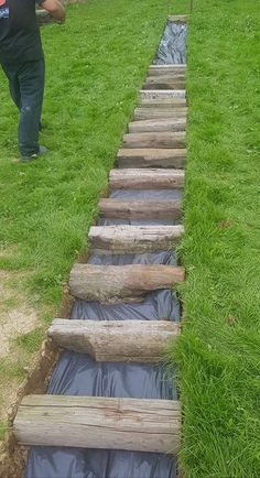 a man is standing in the grass next to some wooden steps that have been dug into the ground