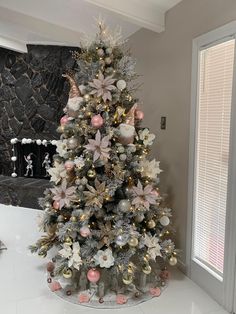 a decorated christmas tree in the corner of a living room with white and pink decorations