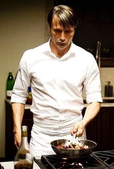 a man standing in front of a stove cooking food on top of a skillet