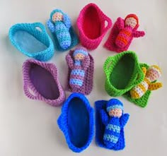 crocheted baby shoes and booties are laid out on a table with one doll in the middle