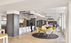 an open concept office with yellow and white chairs, wood floors, and lots of counter space