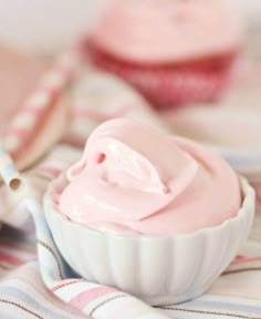 two cupcakes with pink frosting in them on a striped table cloth next to each other