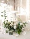 the table is set with white linens and greenery for an elegant wedding reception