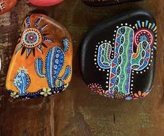 three painted rocks sitting on top of a wooden table