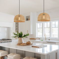 a kitchen island with stools and lights hanging from it's ceiling over it