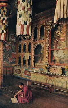 a woman sitting on the floor in front of a wall covered with colorful tapes and curtains