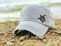 Need to change this cap design to a messy bun/high ponytail cap style, a non-distressed baseball cap or kid's baseball cap? Once you have this cap in your cart, head here: https://etsy.me/2S82fka Distinct Headwear Presents... Women's embroidered sea turtle baseball cap with a petite corner design. Fully embroidered - measures just over one inch tall and is placed in cap corner. Choose your cap and thread colors. Main photos show a light grey cap with a black turtle. We have added medium gold and Turtle Hat, Vacation Clothing, Ponytail Cap, Kids Baseball Caps, Salt Water Fishing, Distressed Baseball Cap, Gray Cap, Mom Hats, Cap Designs