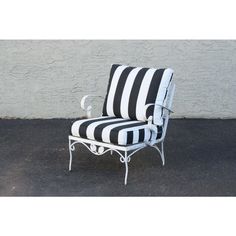 a black and white striped chair sitting in front of a wall with an iron frame