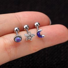 three different types of piercings on someone's finger, one with a star and the other with a moon