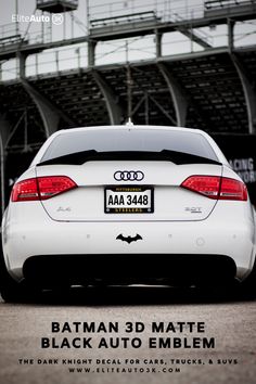 the back end of a white car in front of an empty stadium