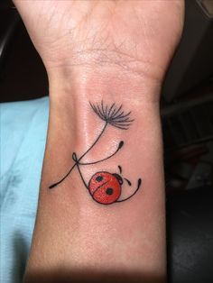 a ladybug tattoo on the wrist with a dandelion in the center