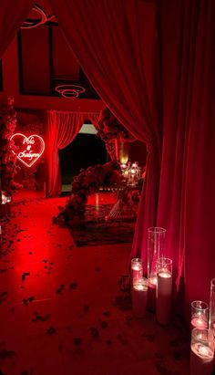 candles are lit on the floor in front of red drapes and curtains with hearts