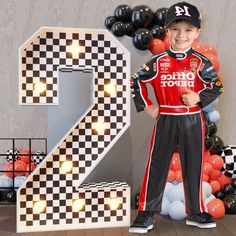 a young boy is posing in front of the number two for his race car themed birthday party