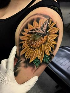 a woman's arm with a sunflower and butterfly tattoo on the left shoulder