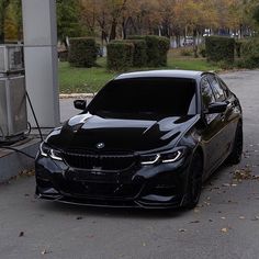 a black car is parked in front of a gas station with an electric charger