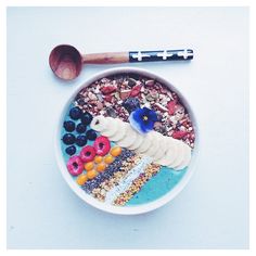 a bowl filled with cereal and fruit next to a spoon