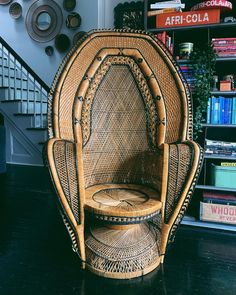 a wicker chair sitting on top of a wooden floor next to a book shelf