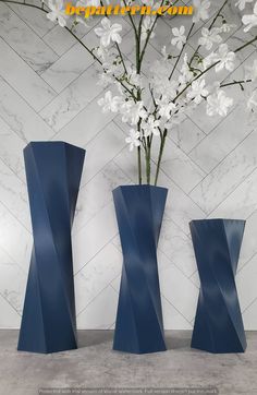 three blue vases with white flowers in them on a marble wallpapered background