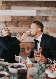 a man and woman sitting at a table eating cupcakes