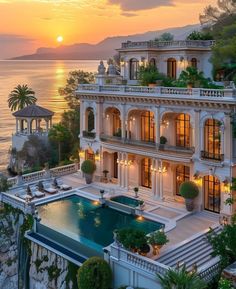 an aerial view of a mansion overlooking the ocean at sunset, with its swimming pool surrounded by greenery