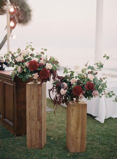 two wooden vases with flowers in them sitting on the grass next to a table