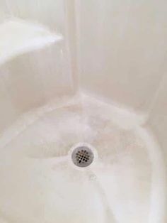 a white sink with water running down it's side and a drain in the middle