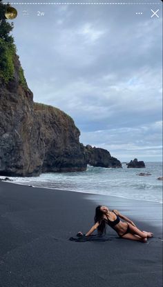 a woman laying on top of a beach next to the ocean