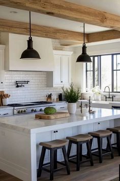 a kitchen island with stools in front of it and lights hanging from the ceiling