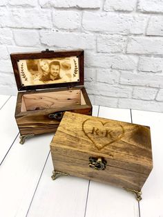 an open wooden box with two pictures in it on a white table next to a brick wall