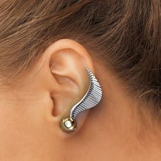 a close up of a person's ear wearing a pair of silver and gold earrings