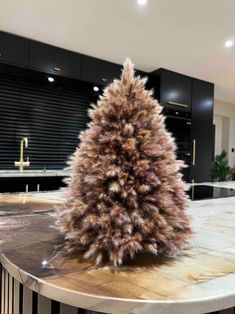 a small christmas tree sitting on top of a table in front of a kitchen counter