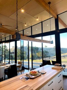 an open kitchen and dining room with large windows looking out onto the mountains outside at sunset