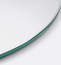 a close up view of a circular mirror on a white surface with green trim around the edge