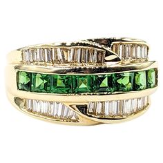 Channel Set .54ctw Tsavorite Garnets & .75ctw diamonds Ring In Yellow Gold This striking Gemstone Fashion Ring, artfully crafted in 14kt Yellow gold, boasts a vibrant .54ctw Tsavorite Garnets centerpiece, beautifully complemented by .75ctw baguette diamonds set in a sleek channel. These diamonds are of SI clarity, exhibiting a near-colorless white hue that enhances the ring's allure. The harmonious blend of the vivid green tsavorite garnets with the sparkling diamonds makes this piece truly capt Classic Green Multi-stone Diamond Ring, Green Multi-stone Diamond Ring, Green Cluster Diamond Ring For Anniversary, Emerald Cut Green Diamond Ring With Multi-stone, Emerald Cut Green Multi-stone Diamond Ring, Green Emerald Cut Multi-stone Diamond Ring, Green Emerald-cut Diamond Ring Channel Set, Green Emerald Cut Diamond Ring Channel Set, Green Baguette Cut Ring With Diamond Accents