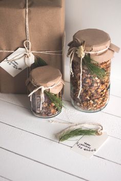 two jars filled with granola sitting on top of a table next to a brown bag