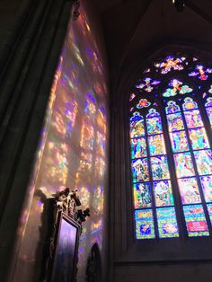 sunlight streaming through the stained glass windows in an old church, with a mirror on the wall