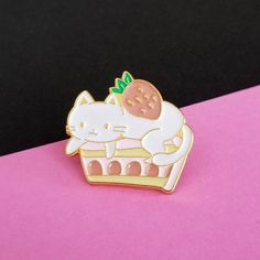 a white cat sitting on top of a strawberry filled cake pin with the word hello kitty written below it